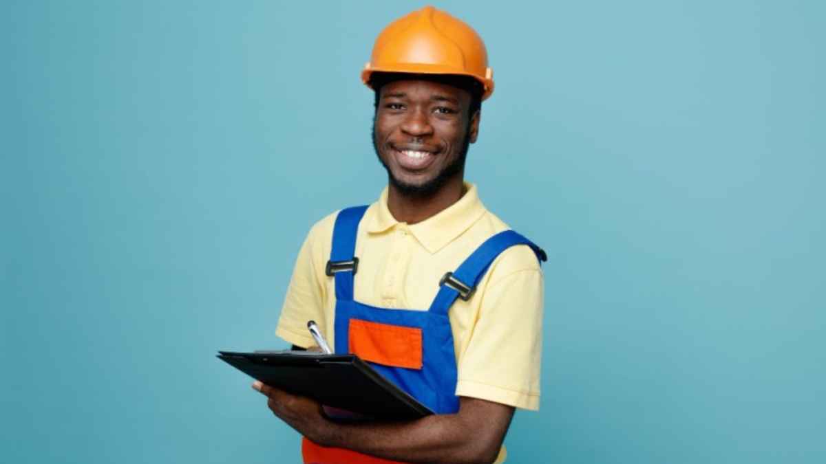 laughing-young-african-american-builder-uniform-holding-clipboard-isolated-blue-background