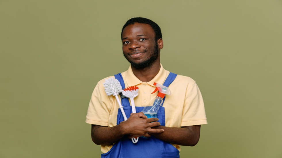 pleased-holding-cleaning-tools-young-africanamerican-cleaner-male-uniform-with-gloves-isolated-green-background (1)